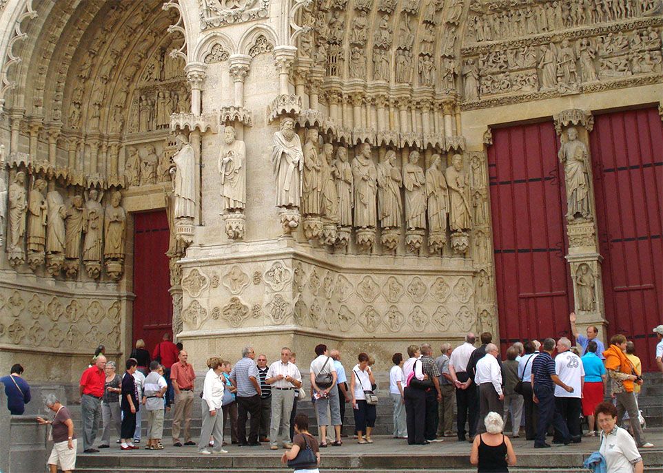 Cette photo de Pascale Marcotte montre un guide touristique demandant l'attention d'un groupe de visiteurs réunis devant la magnifique façade de la cathédrale gothique Notre-Dame d'Amiens, en France. Celle-ci est la plus vaste cathédrale de France.