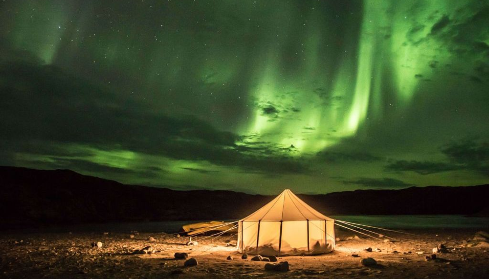 <p>Scène de nuit au Nunavik, au bord d’un lac du parc national Tursujuq. Une tente inuite en canevas apparaît sous la splendeur d’une aurore boréale dans le ciel polaire.</p>