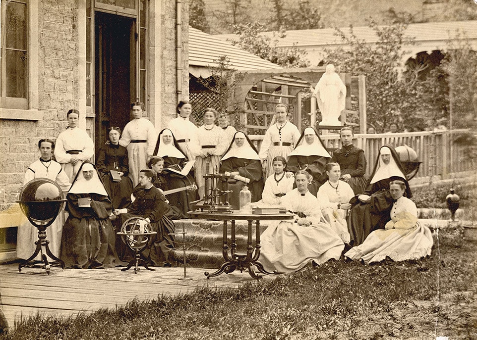 Un photographe est passé chez les Ursulines de Québec en 1867. Il a laissé cette image des religieuses enseignantes et des élèves d’une classe de sciences. Parmi les objets mis en scène, nous retrouvons notamment un globe terrestre et une sphère armillaire. Une machine pneumatique pour recréer le vide et un gros livre sont posés sur une table. Une élève tient une guitare.