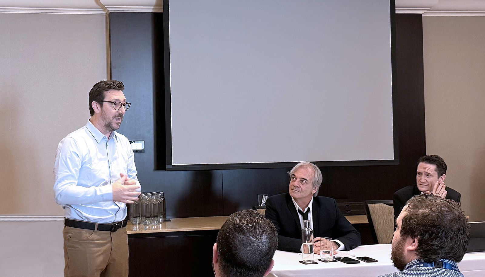 <p>Le professeur Stéphane Roche intervient à l’occasion d’un échange entre des représentants de la société civile québécoise et le ministre de l’Environnement et de la Lutte contre les changements climatiques du Québec Benoît Charrette (assis, à droite). L’activité, une séance de questions-réponses avec ce dernier, était animée par l’émissaire aux changements climatiques et aux enjeux nordiques et arctiques du gouvernement du Québec, Jean Lemire (assis, à gauche).</p>