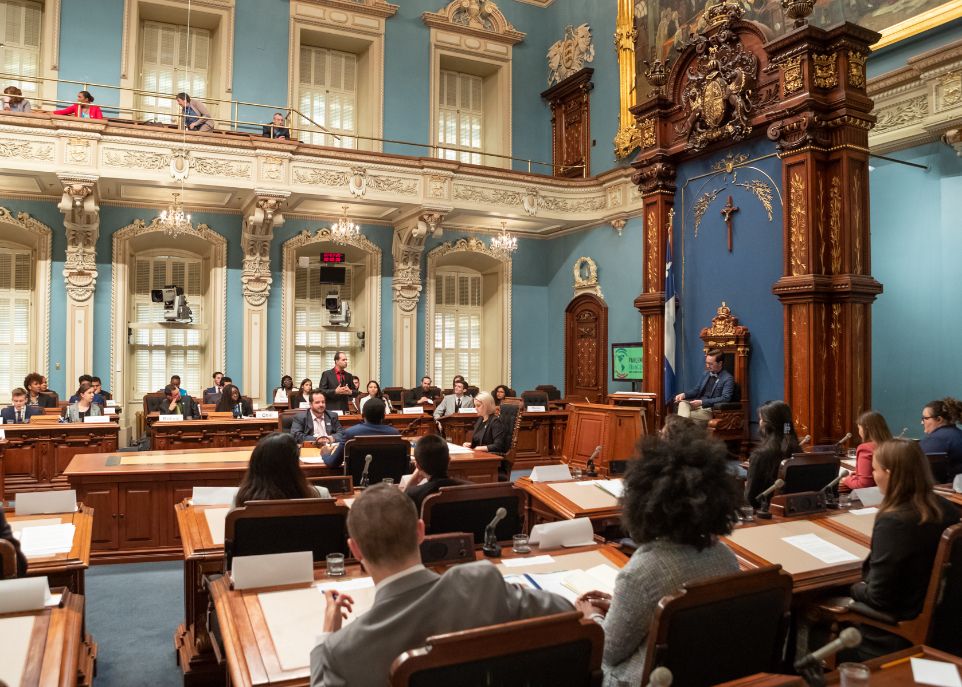 Le Parlement francophone des jeunes des Amériques s'est déroulé en partie au Salon bleu de l'Assemblée nationale du Québec. Sur la photo, Philippe Dubois est assis sur le siège du président de l'Assemblée nationale. Cécile Gagnon est devant lui, à l'extrémité de la table.