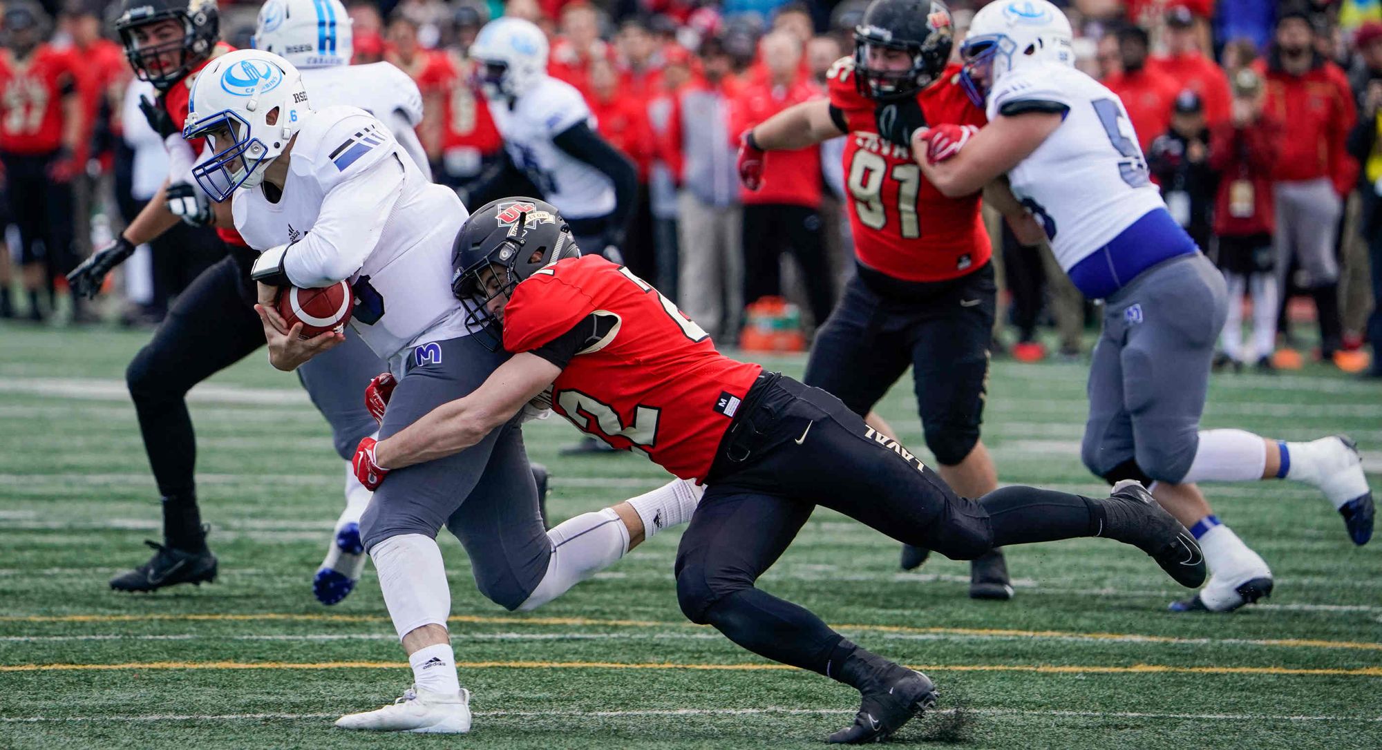 Le footballeur Maxym Lavallée, du Rouge et Or, intercepte un joueur des Carabins de l'Université de Montréal.