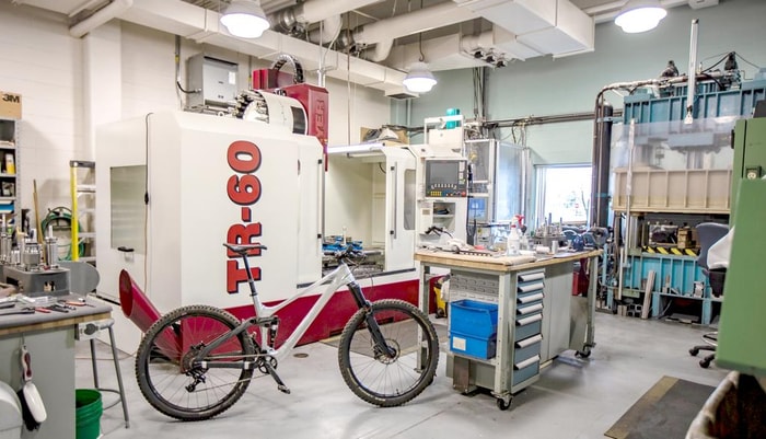 <p>William Boisvert a réalisé ce premier cadre de vélo de montagne, notamment avec deux collègues, dans un laboratoire de l’Université Laval. À l’arrière: la machine à commande numérique utilisée durant le projet. L’entreprise Tool fabrique des cadres et des composantes faits d’aluminium machiné. Ils sont assemblés par collage. Ces produits sont fabriqués selon des valeurs de solidité, de beauté et d’écoresponsabilité.</p>