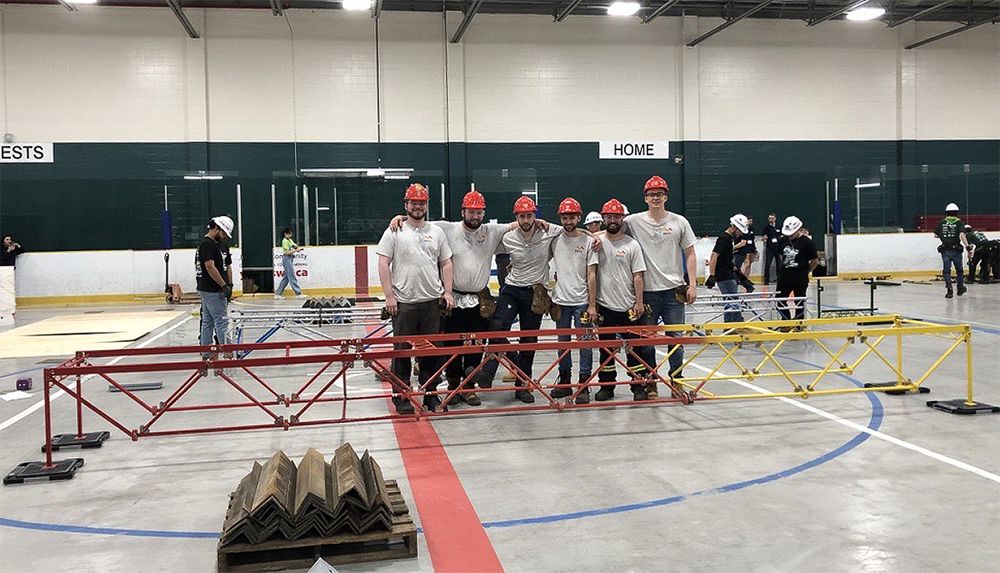 L’équipe de «bâtisseurs» posant derrière le pont de l’Équipe de structure de l’Université Laval après avoir terminé sa construction lors de la Compétition nationale canadienne de pont d’acier 2023.