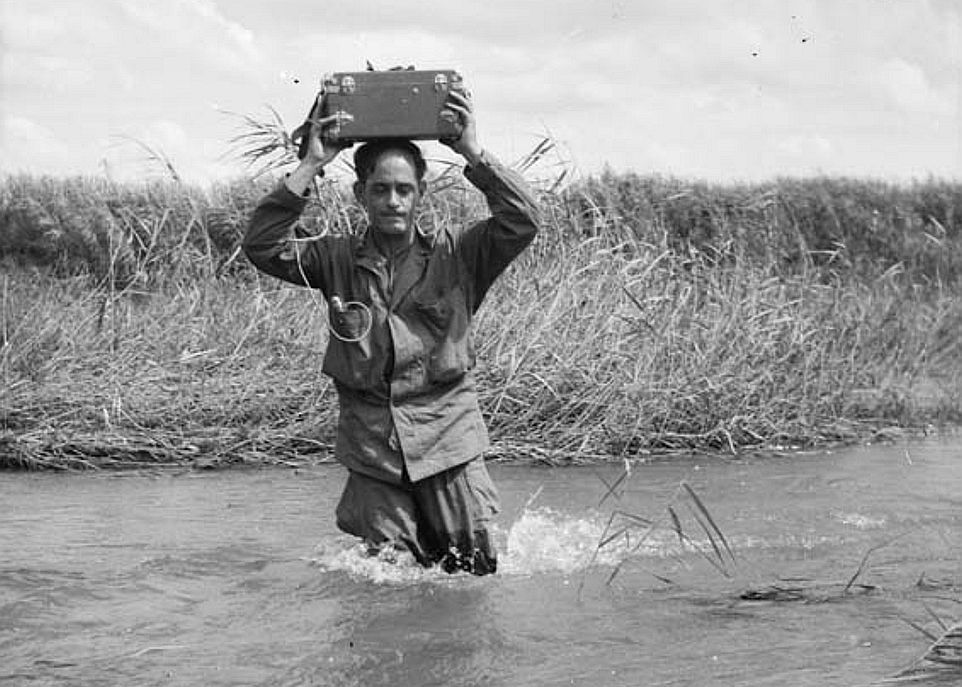 Le journaliste René Lévesque, durant la guerre de Corée, le 14 août 1951. Il franchit un cours d'eau, en territoire ennemi, en portant son enregistreuse sur sa tête, en direction du Royal Canadian Regiment, un régiment d'infanterie légère canadien.