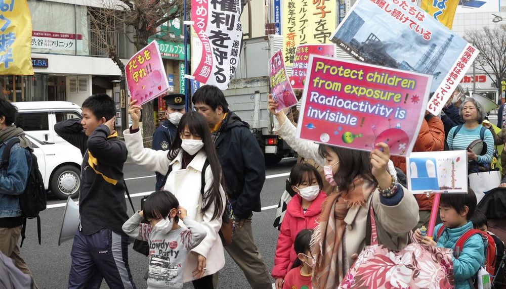 Des manifestants à Tokyo, après l’accident nucléaire, demandent l’évacuation des enfants de la ville de Fukushima. La pancarte en anglais se lit comme suit: «Protégez les enfants de l’exposition [aux radiations]! La radioactivité est invisible!»