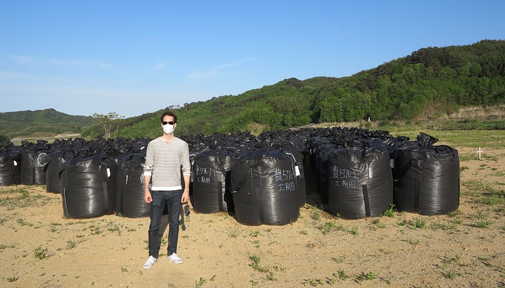 <p>Le professeur Polleri pose devant une grande quantité de sacs de plastique contenant de la terre radioactive. Ces amoncellements sont le résultat des politiques de décontamination du gouvernement japonais.</p>