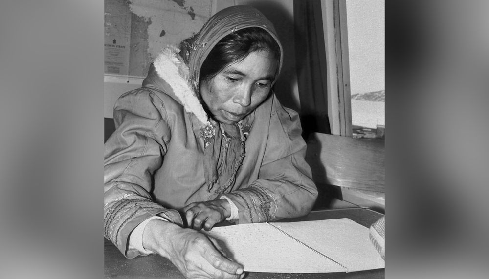 Avril 1966. Mitiarjuk Nappaaluk lit l'un des cahiers où elle a écrit Sanaaq. Sur la table est posé un magnétophone. Par la fenêtre, on peut voir la banquise qui recouvre la baie à cette période de l'année.