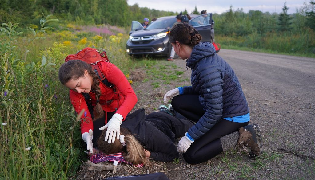 Le soir du 12 août, lors d'une simulation dans la pourvoirie Seigneurie Nicolas-Riou, des étudiantes portent secours à une femme gisant sur le bord du chemin pendant que d'autres s'occupent des occupants de la voiture toute proche.