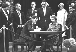 <p>La cérémonie de signature, en 1982, sur la colline parlementaire d'Ottawa, de la proclamation visant le rapatriement de Londres de la Constitution canadienne et sa révision subséquente. Le ministre de la justice, Jean Chrétien, s'exécute face à la reine Elizabeth II. Derrière lui, troisième à partir de la gauche, le premier ministre Pierre Elliot Trudeau.</p>