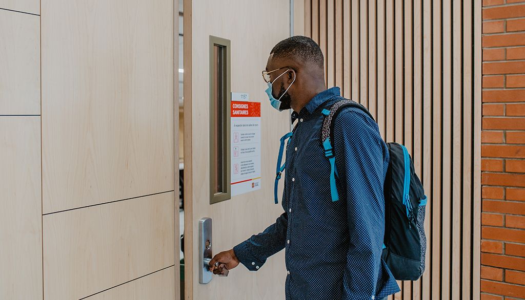 Un étudiant portant un masque chirurgical entre dans une salle de classe