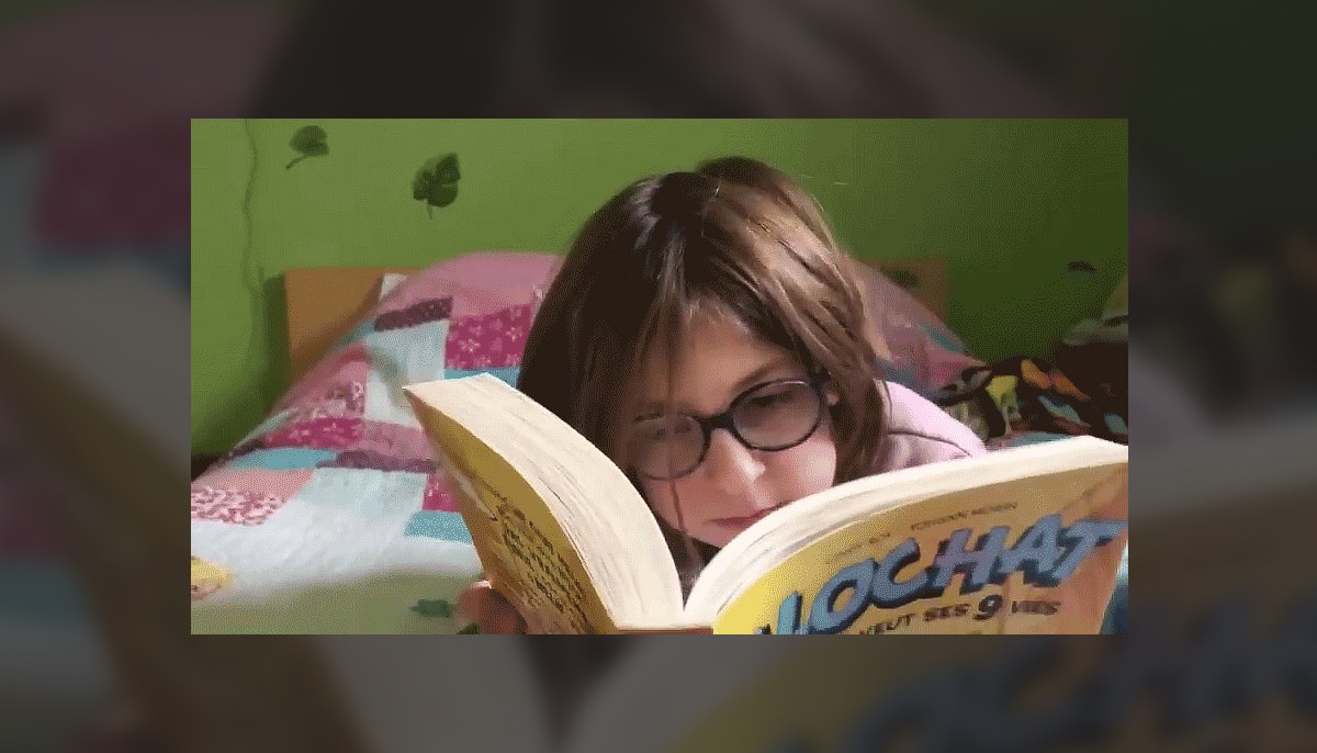 Philomène Boucher aura dix ans cette semaine. Cette jeune lectrice a été filmée par Daisy Pelletier il y a deux ans durant le tournage de la vidéo de présentation de la doctorante pour le concours du CRSH. Sur cette capture d’écran, l’enfant lit le tome 1 de Clochat veut ses neuf vies. Philomène aime plus ou moins lire d’elle-même parce que cela lui demande un effort énorme. Par contre, elle a toujours adoré que sa mère lui fasse la lecture, surtout le soir, dans le lit. Elle a dû travailler fort pour le décodage, mais elle s’améliore enfin. Elle a aussi quelques coups de coeur qui lui donnent envie de lire. Elle est partagée entre lire des livres de son niveau, qu'elle trouve trop «bébé», et lire des livres plus difficiles, qu’elle trouve «cool». Elle a accroché sur plusieurs mangas, pour imiter sa soeur aînée au départ, et par intérêt par la suite. Bref, elle commence à prendre plaisir à lire et à mieux comprendre l’importance de la lecture.