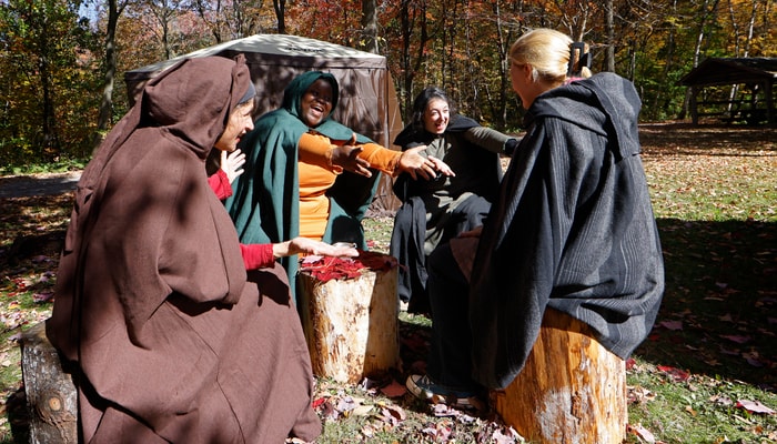 Sur la place centrale, les trois chamanes interprétées par Claudia Pelletier, Josiane Nguimfack et Claudia Funchal chantent Here comes the sun avec la journaliste Manon Plante.