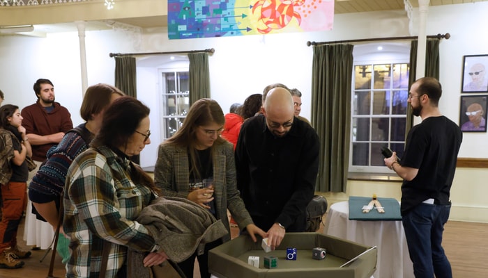 Dans le module interactif Le voile d'ignorance, les participantes et participants sont invités à lancer les dés pour mieux comprendre comment le hasard détermine l'identité sociale de chaque personne: genre, origine, niveau de richesse, religion et talents. Le philosophe John Rawls croit que si les gens qui organisent la société ignoraient leur identité sociale, ils opteraient pour une société plus équitable pour toutes et tous. À l'arrière, on aperçoit l'œuvre de Christine Sioui-Wawanoloath sur la violence épistémique.