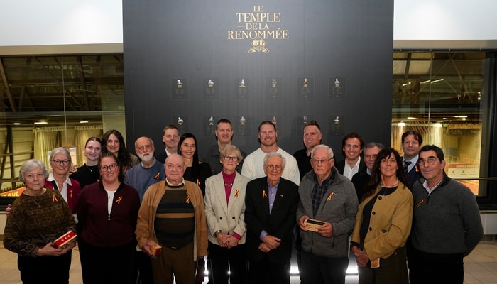 Les personnes intronisées au Temple de la renommée du Rouge et Or devant le mur commémoratif qui porte leurs noms, lors de la cérémonie du mercredi 10 décembre