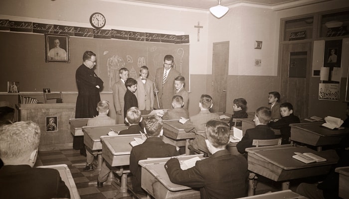 Visite d’un inspecteur dans une classe de garçons à Montréal. Cette photo est l'oeuvre d'Edmond Mount, en 1957. Chaque année, les inspecteurs visitaient les nombreuses écoles du Québec pour s’assurer, entre autres, que les lois scolaires étaient respectées et pour évaluer les maîtres et les maîtresses.