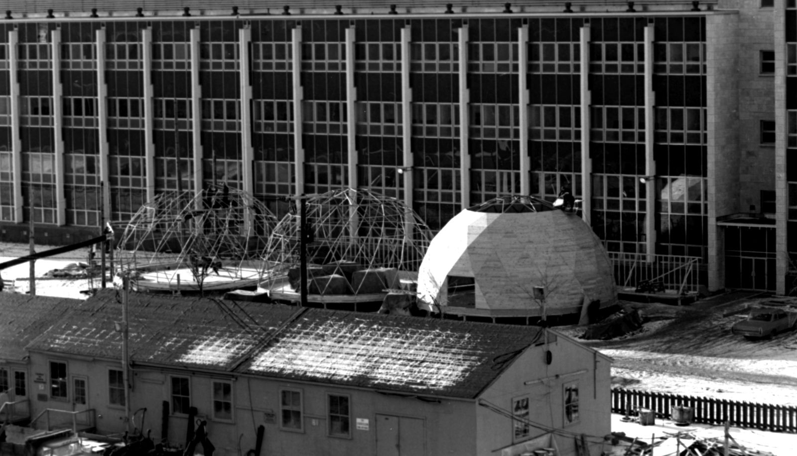 Assemblage des dômes devant le pavillon Adrien-Pouliot en 1967. Recouvertes d'une membrane blanche imperméable, ces structures de bois ont été montées par le Service des terrains et bâtiments de l'Université Laval, assisté d'étudiants en architecture.