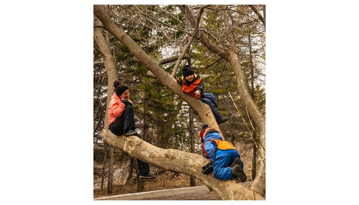 Une éducatrice d’un centre de la petite enfance avec deux jeunes enfants, dans un arbre