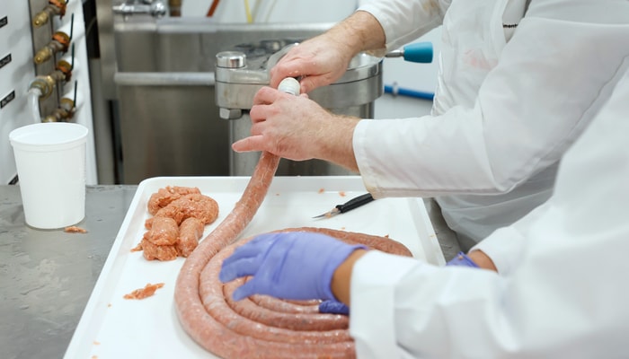 Les membres de Carnivore remplissent les boyaux avec la chair à saucisses.