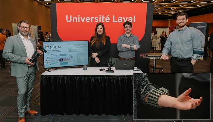 Le professeur Benoit Gosselin, affilié au Centre de recherche CERVO et au Centre interdisciplinaire de recherche en réadaptation et intégration sociale (Cirris), la professeure Véronique Flamand, affiliée au Cirris, les doctorants Étienne Michaud et Félix Chamberland, avec la main robotique présentée au kiosque du Centre de recherche en robotique, vision et intelligence machine. Le bracelet renferme les 64 électrodes qui captent les contractions musculaires responsables du mouvement de la main.