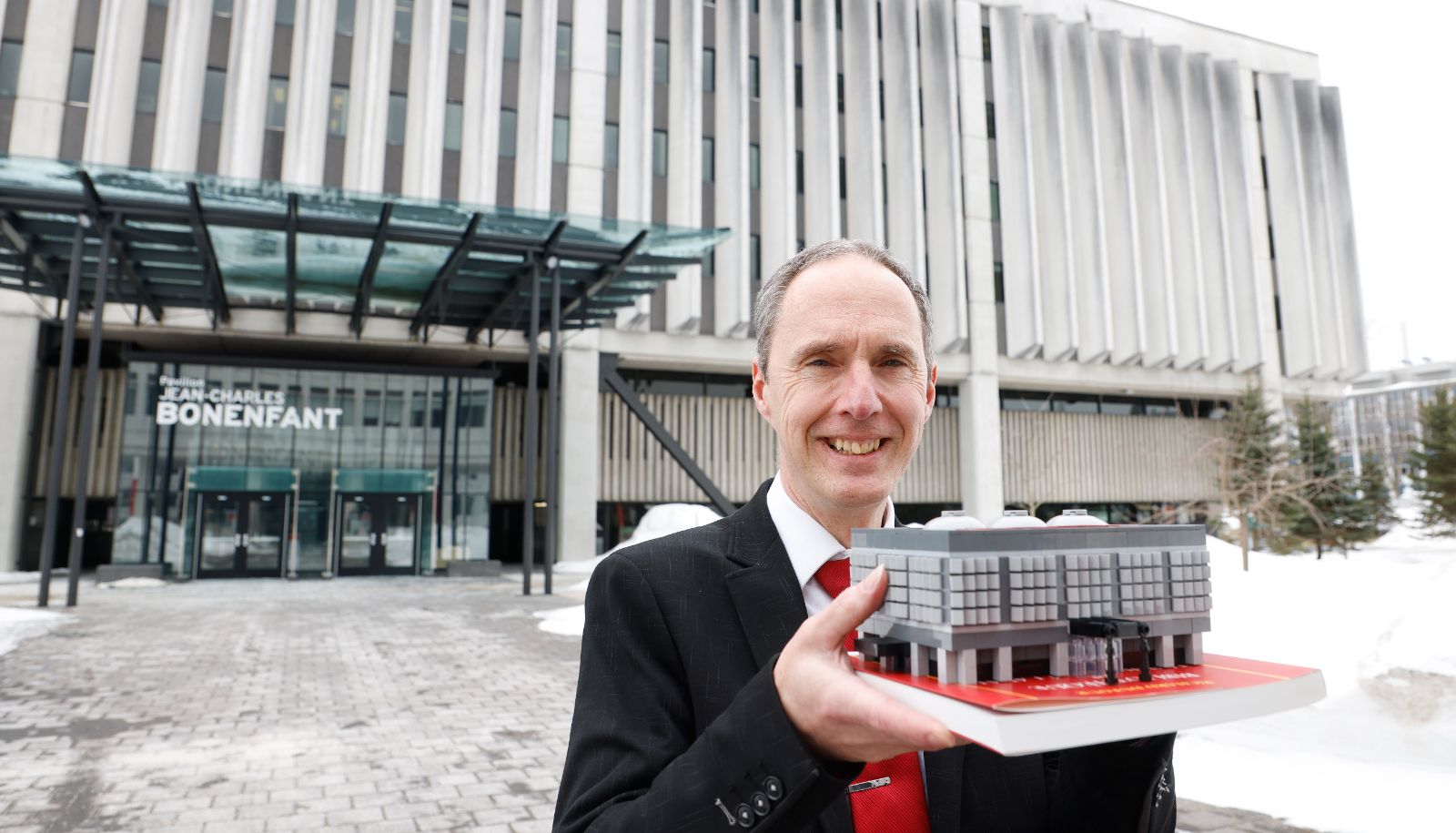 Richard Dufour devant le pavillon Jean-Charles-Bonenfant, qui lui a inspiré cette construction en blocs LEGO.