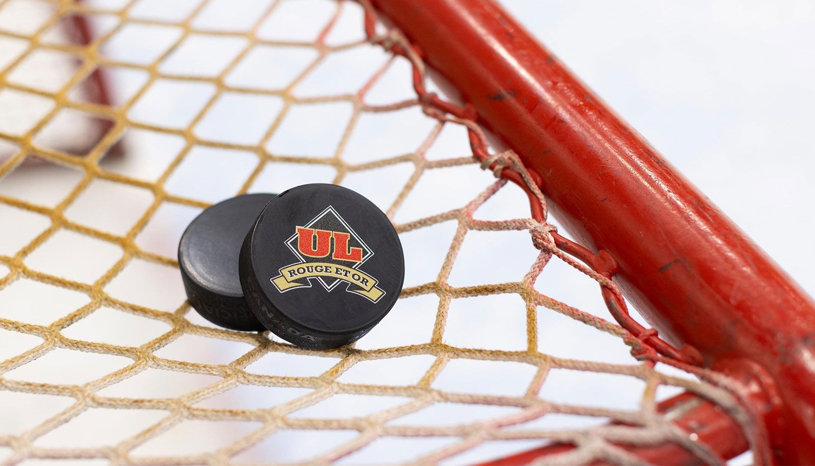 Une rondelle de hockey arborant le logo de l'Université Laval, sur le dessus d'un filet de hockey.