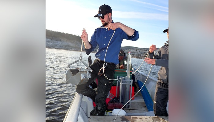 Gabriel St-Pierre qui échantillonne des insectes aquatiques dans les sédiments de la Grande rivière de la Baleine en août 2022.