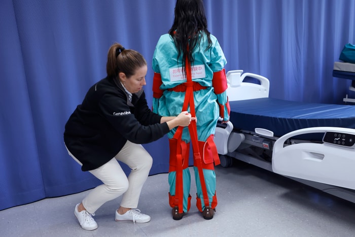 Geneviève Côté, responsable de travaux pratiques et de recherche, resserre les sangles de la combinaison gériatrique portée par Vanessa Massicotte, technicienne spécialisée en simulation.