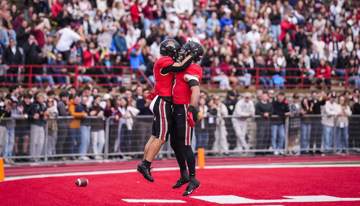 Deux joueurs du club de football Rouge et Or de l'Université Laval célèbrent sur le terrain dans la zone des touchés.