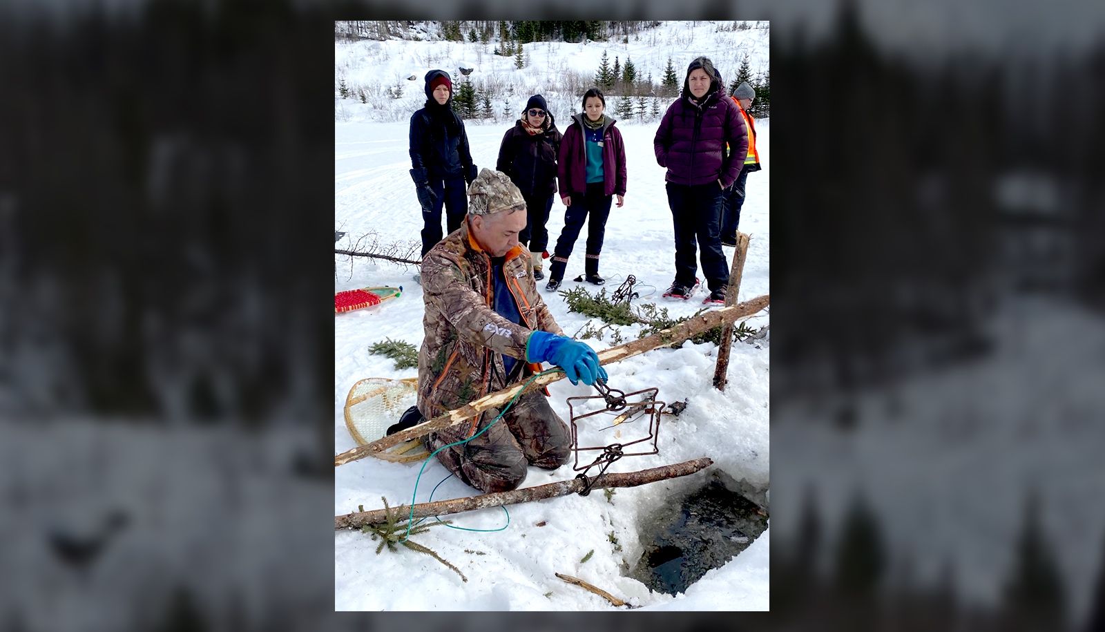 <p>Un formateur innu explique le fonctionnement d’une trappe à castor à des participantes durant le premier séjour en territoire de la cohorte 2023.</p>
