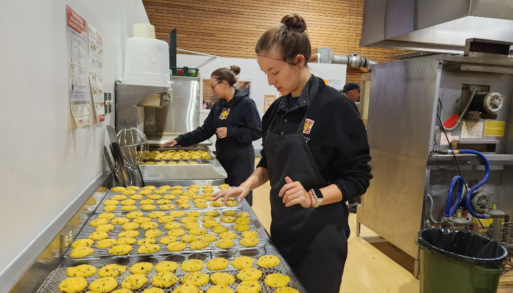<p>Priscilla Tremblay (au fond) et Rose Audet, des Services Web et recrutement étudiant de l'Université, ont préparé galettes de courgettes, tofu teriyaki, muffins et pain de viande à La Baratte, le 12 octobre.</p>