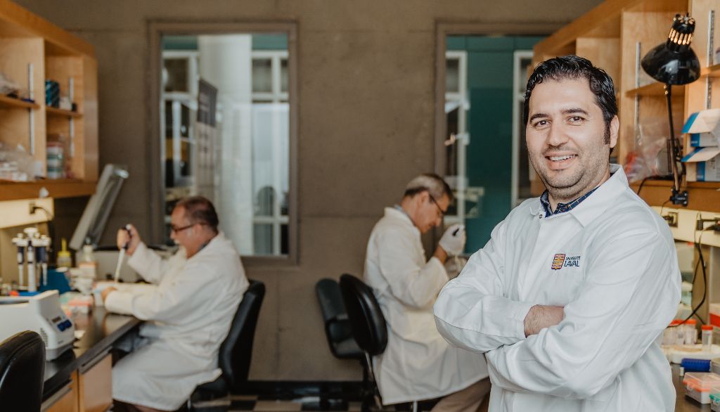 Davoud Torkamaneh dans les locaux qui abritent la Plateforme de séquençage génomique de l'Institut de biologie intégrative et des systèmes de l'Université Laval. Derrière, deux membres de cette équipe, Brian Boyle et Christian Otis.