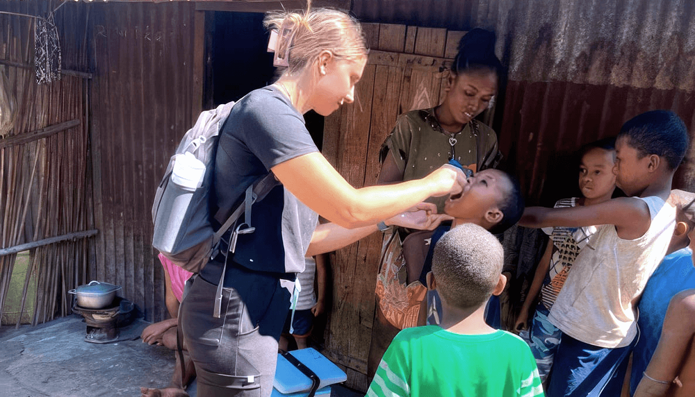 Valérie Dollo sur le terrain, vaccinant contre la poliomyélite, dans le cadre d’une campagne de vaccination en partenariat avec l’UNICEF. Les enfants recevaient deux gouttes de vaccin polio oral.