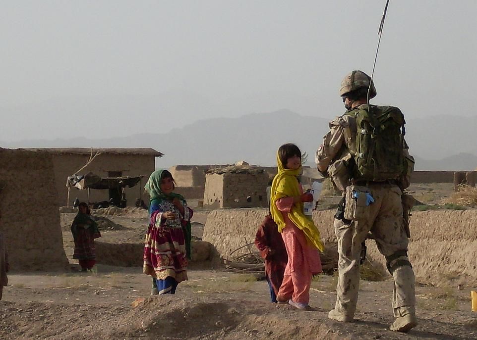 <p>Le fantassin distribue des bouteilles d'eau à des enfants lors d'une mission en Afghanistan.</p>
