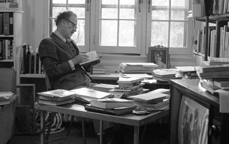 Marshall McLuhan chez lui, à Toronto, en 1972, entouré de livres et d'un téléviseur allumé.