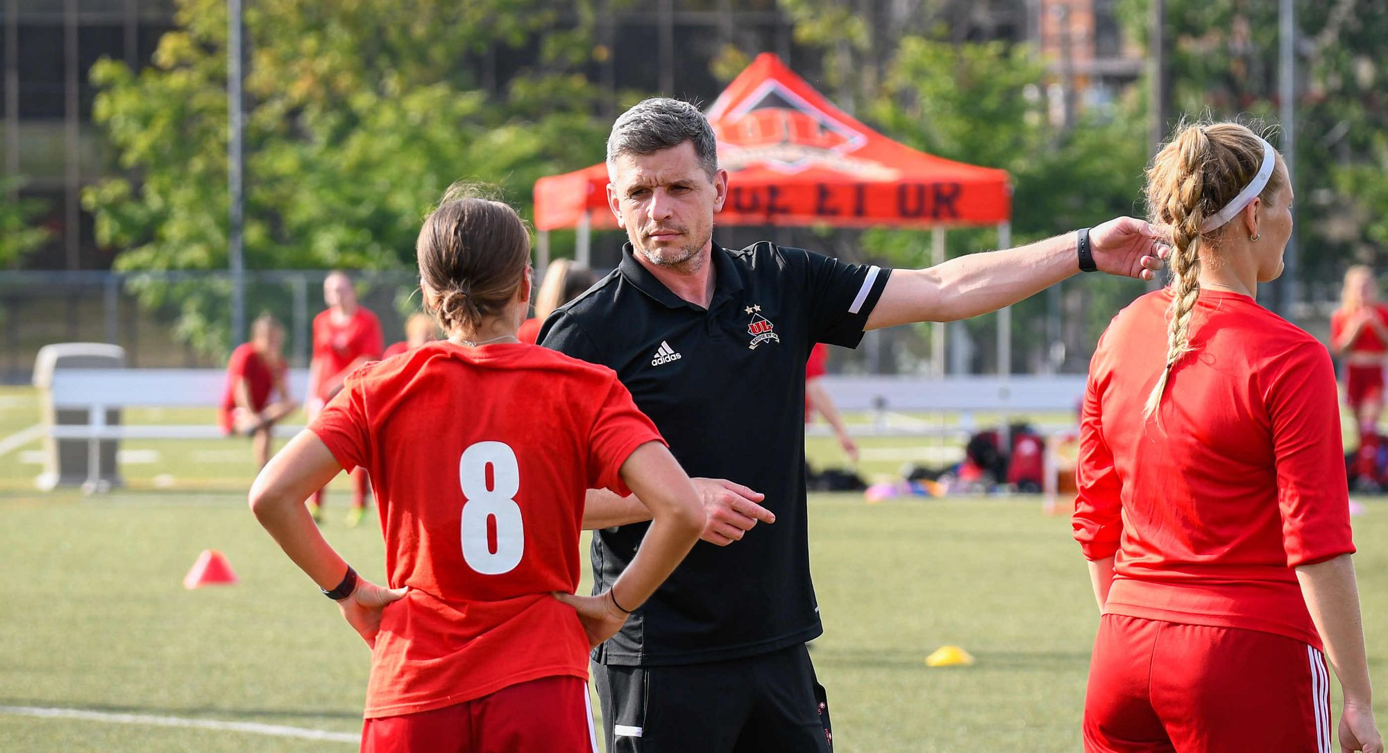 David Desloges, entraîneur du club de soccer féminin Rouge et Or, avec 2 joueuses de son équipe.