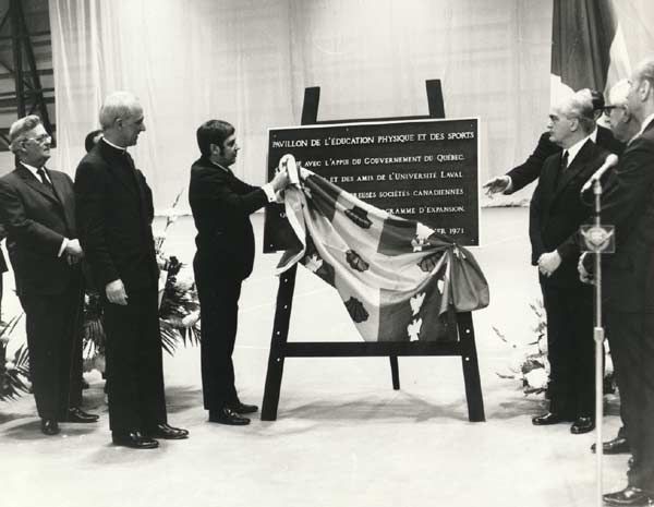 <p>L'inauguration du PEPS en 1971 a été immortalisée par une plaque commémorative, dévoilée en présence de nombreux dignitaires, dont Napoléon Leblanc, vice-recteur aux affaires professorales et étudiantes, Mgr Louis-Albert Vachon, recteur, Gilles Houde, adjoint parlementaire du ministre de l'Éducation et responsable du Haut-Commissariat à la jeunesse, aux loisirs et aux sports et représentant du premier ministre, et Louis-Philippe Bonneau, vice-recteur exécutif (de gauche à droite sur la photo).</p>