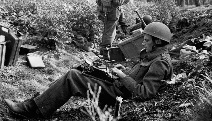 <p>Durant la Seconde Guerre mondiale, le journaliste australien Alan Wood était correspondant de guerre pour le journal britannique Daily Express. Il est photographié en train de taper une dépêche à la machine, cigarette au bec, pendant que des soldats britanniques consultent une carte à l’arrière. Le moment est le 18 septembre 1944 au cours de la bataille pour la prise de la ville d’Arnhem, aux Pays-Bas.</p>